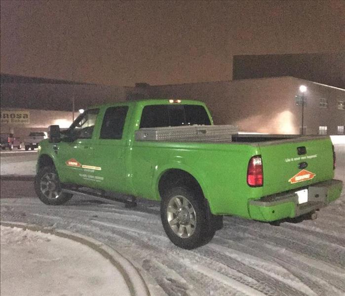 SERVPRO pickup truck in snow covered parking lot at a commercial loss in the middle of the night
