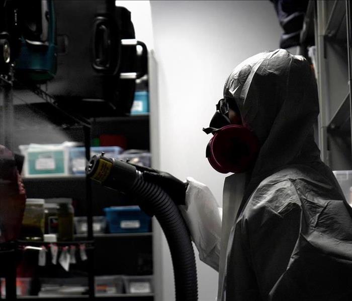 man in protective equipment sprays room 