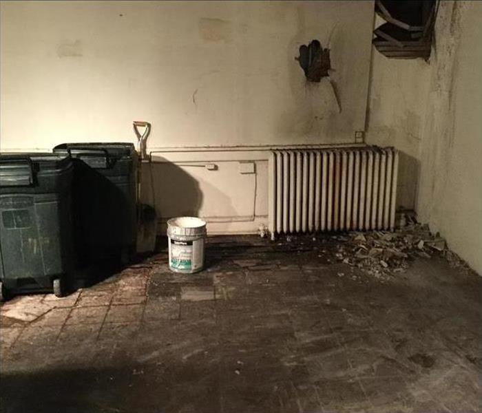 room, two plastic garbage cans, a white bucket, holes in the wall, 