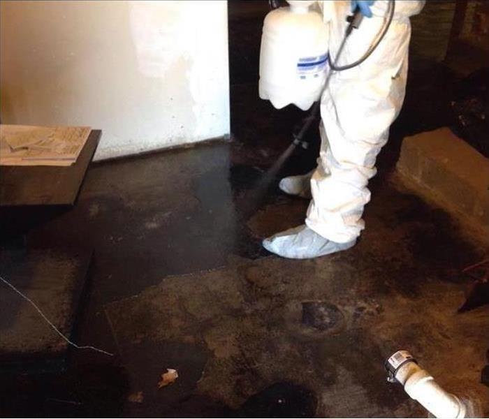Worker with protective gear while sanitizing floor, wet floor, floodwater