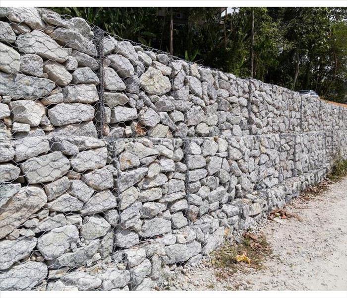 Slope and earth retention wall management with rocks and wire mesh cage system in tropical hilly terrain