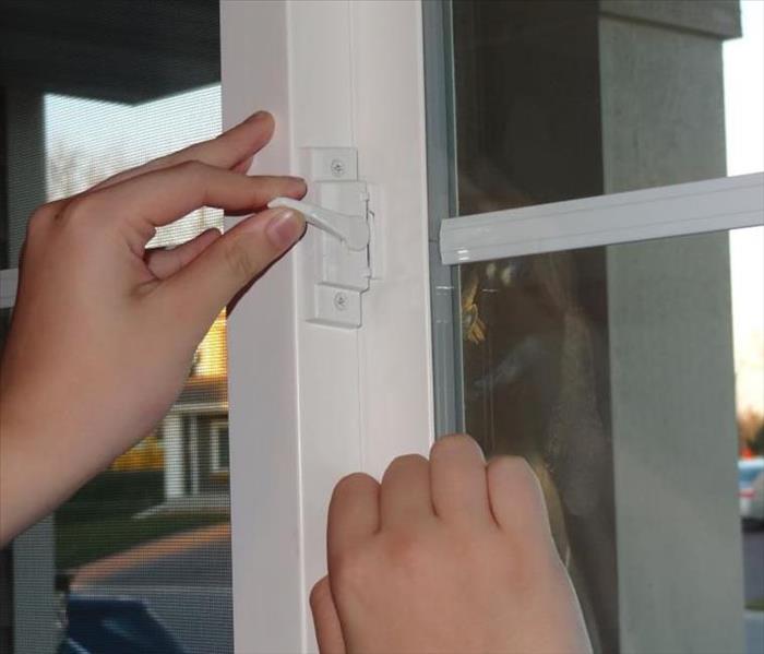 Hands shutting a window latch to prepare for winter weather